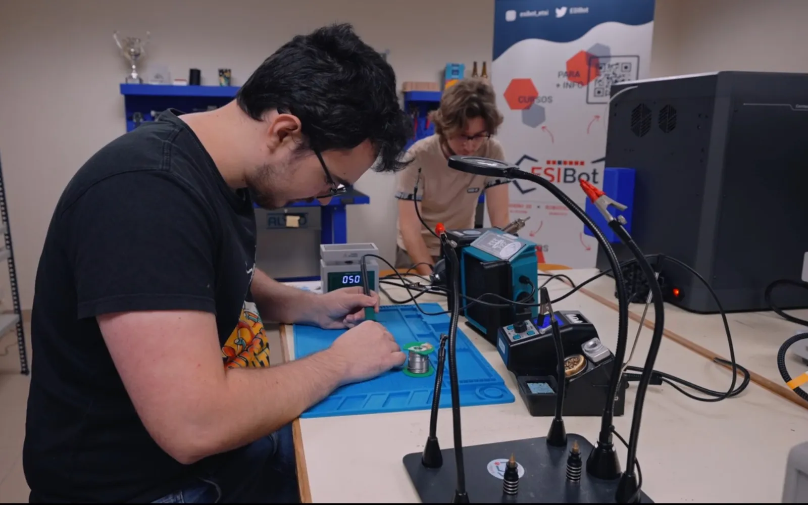 Miembros de ESIBot soldando componentes en el taller